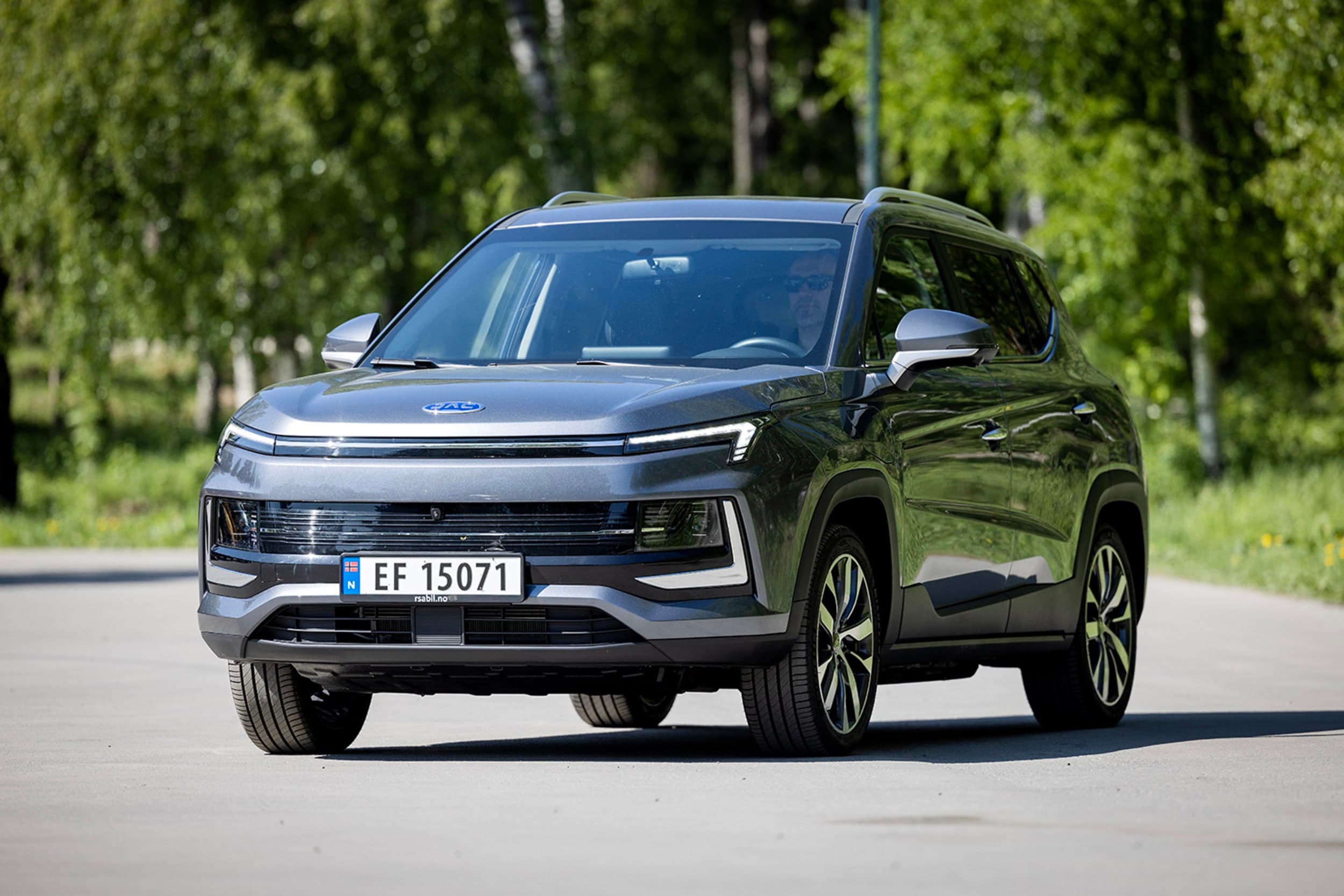 Grå JAC e-JS4 foran grønne busker