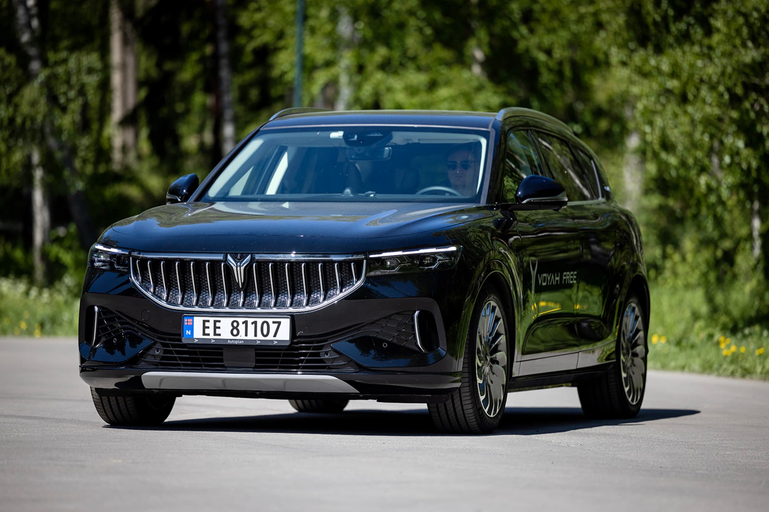 Svart Voyah Free foran grønne busker