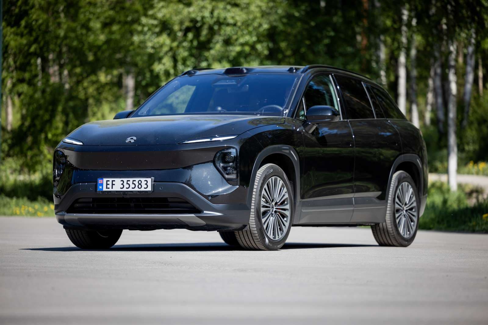 Sort NIO EL7 foran grønne trær